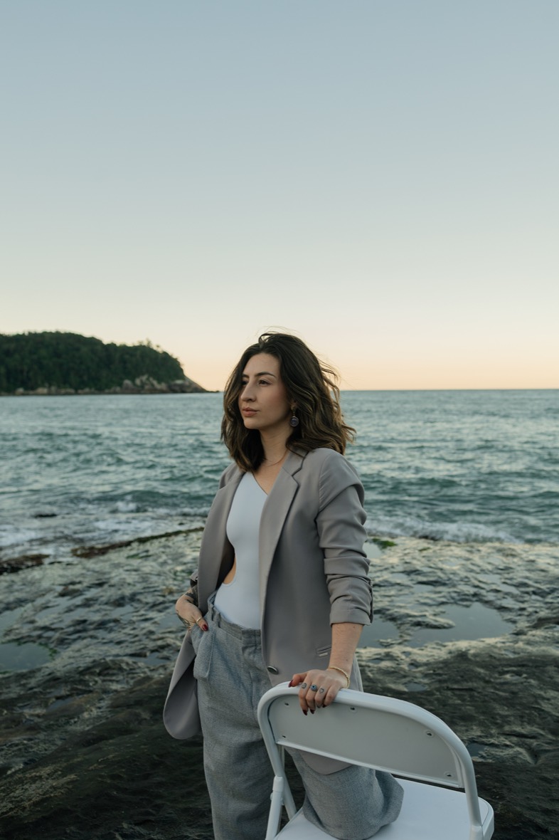 Registro do Patroa Day — mulher de blazer à beira-mar no fim de tarde.